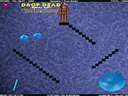 Drop Dead: Final Cut game screenshot showing a teddy bear being launched toward a complex trap of spinning blades and crushing gears in a physics-based puzzle level. Play free online game.