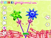 Screenshot of Candy Lollipops Maker game showing hands decorating a colorful, freshly made candy lollipop with sprinkles and toppings.