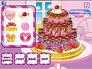Screenshot of Surprise Birthday Cake game showing a brightly decorated, multi-layered birthday cake with fresh fruit, figurines, and custom frosting patterns.