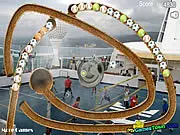 Screenshot of Sport Zuma Online game showing a chain of colorful sport balls (football, basketball) moving across a modern stadium field.