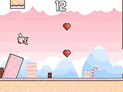 Play Lovely Bird free online game, showing a flapping bird collecting red hearts and rainbow power-ups in the sky.