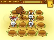 Gameplay screenshot of the free online game Rabbit Invaders, showing a hand with a mace about to hit cartoon rabbits popping out of their burrows.