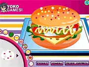 Angel Wings Sandwich Maker free online game screenshot showing a large, multi-layer sandwich being built with various ingredients like lettuce, tomatoes, and meat.