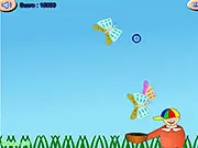 A butterfly falling towards a woven basket in the free online arcade game Basket Butterfly, with a sunny green field background