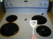 Ilya's Stove gameplay screenshot showing roaches crawling on a stovetop with a cursor ready to squish them. Free online reflex and tapping game.